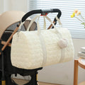 Grand sac à langer beige suspendu à une poussette