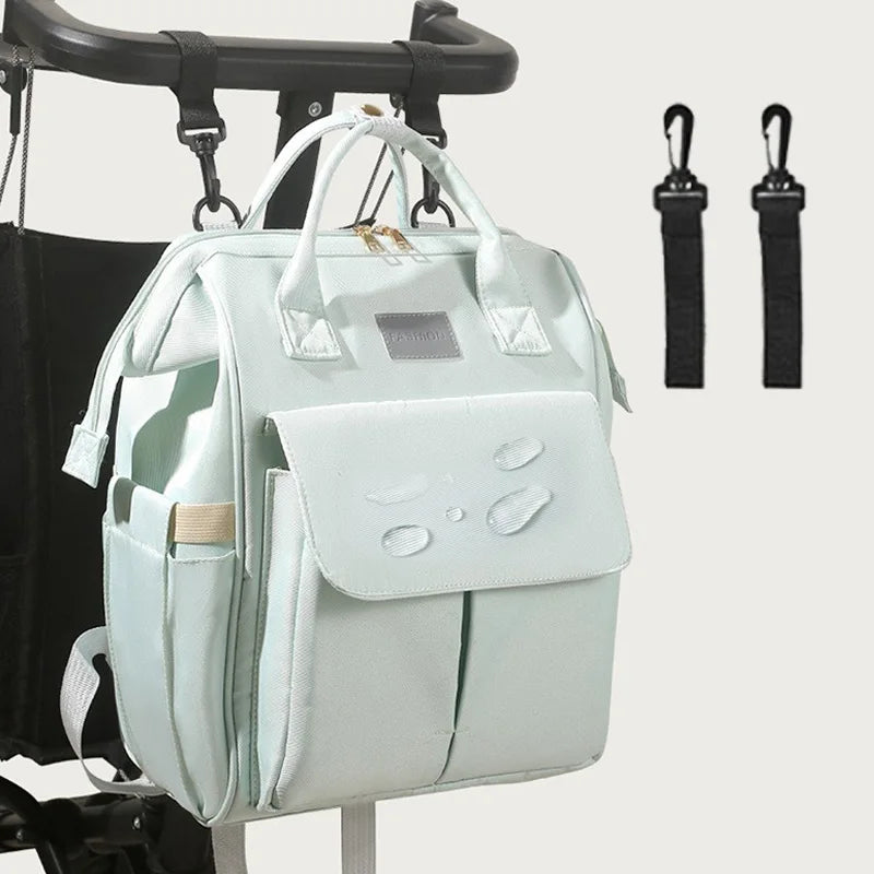Sac à dos à langer menthe suspendu à une poussette