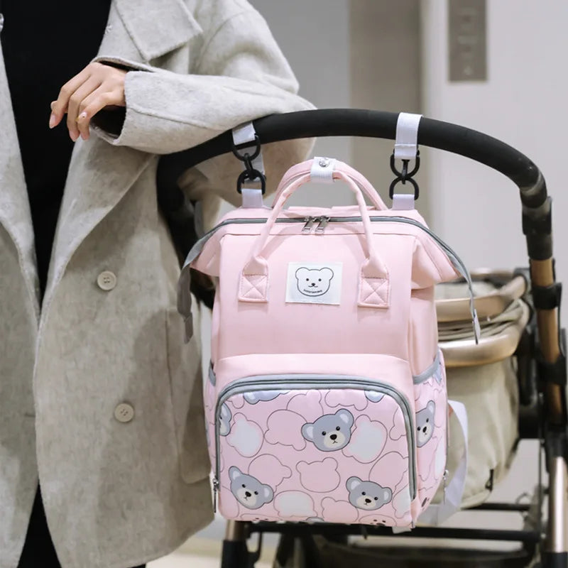 Sac à langer ourson rose attaché à une poussette
